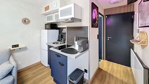 A compact kitchen with white cabinets, a microwave, a sink, and a small trash bin. - Studio with small terrace on first floor (Amiens)