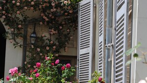 Un edificio con un muro cubierto de rosales y contraventanas.