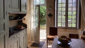 Una habitación con un ventanal grande, una puerta que da al exterior y una mesa con un cuenco de fruta.