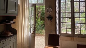Una habitación con techo de madera, una ventana con vistas a vegetación, una mesa con frutero, y una puerta que da al exterior.