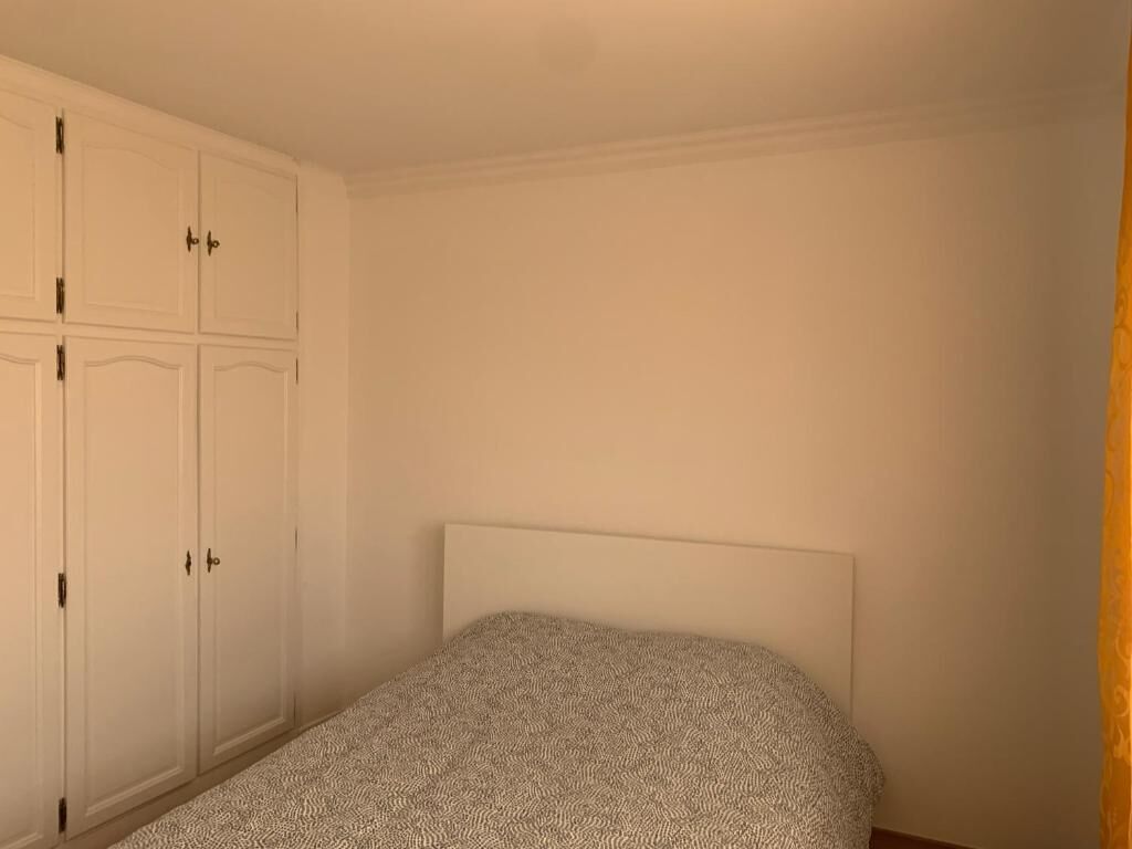 A bedroom with a bed, a wardrobe, and a plain wall.