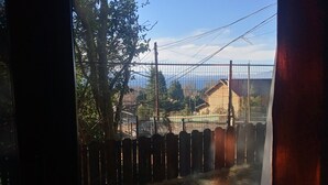 A view through a window with a wooden fence, a metal gate, and a building in the background. - Casa 2 en Bariloche en un Barrio residencial muy tranquilo cerca de todo (San Carlos de Bariloche)