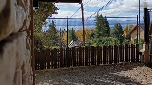 A stone building with a wooden fence and a view of houses and trees. - Casa 2 en Bariloche en un Barrio residencial muy tranquilo cerca de todo (San Carlos de Bariloche)