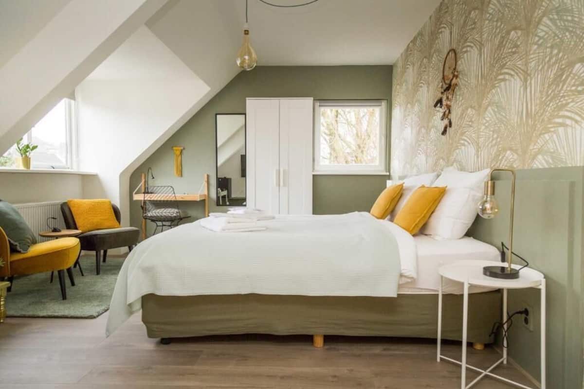 A bedroom with a bed, a desk, a chair, a wardrobe, and a window.