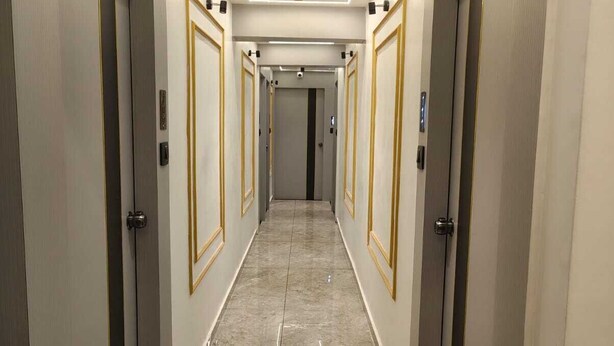 A hallway with doors on both sides, a tiled floor, and a ceiling with recessed lighting.