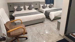A hotel room with two beds, a chair, a nightstand, and an air conditioning unit.