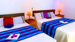 Two single beds with striped bedding, bedside lamps, and a nightstand with a phone. - Aloe Home Stay (Sigiriya)
