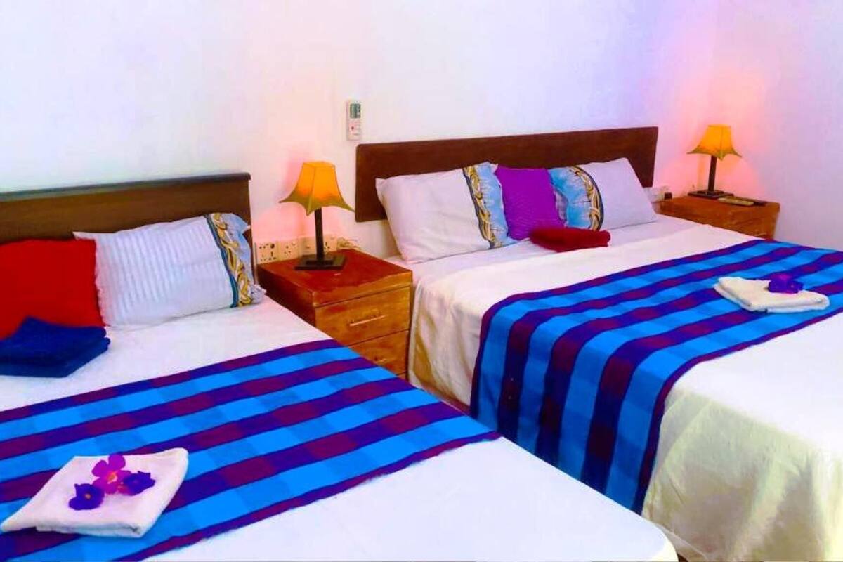 Two single beds with striped bedding, bedside lamps, and a nightstand with a phone.
