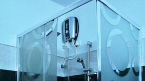 A glass-enclosed shower stall with a handheld showerhead and a handheld shower attachment. - Aloe Home Stay (Sigiriya)