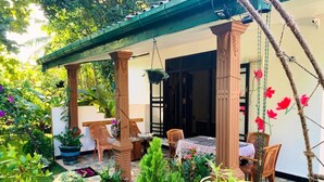 A covered patio area with outdoor seating, potted plants, and a hanging flower arrangement. - Aloe Home Stay (Sigiriya)