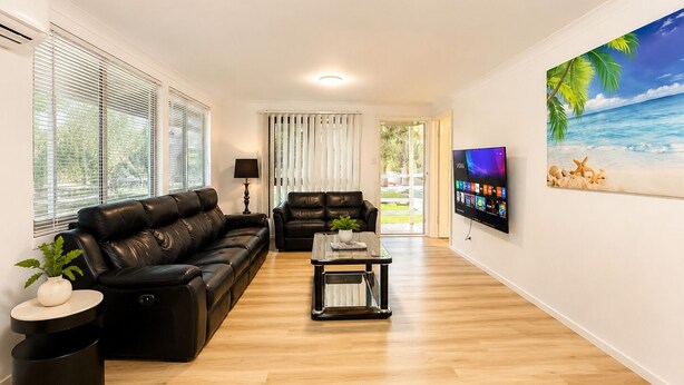 Een moderne woonkamer met een leren bank, een salontafel en een flatscreen televisie aan de muur.