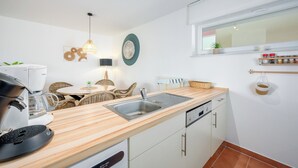 Eine moderne Küche mit Holzarbeitsplatte, Edelstahlspüle und weißen Schränken.