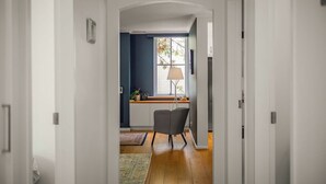 Un pasillo que conduce a una habitación con ventana, lámpara y sillón.