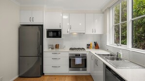Una cocina moderna con armarios blancos, electrodomésticos de acero inoxidable y un ventanal con vistas al exterior.