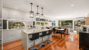 A modern kitchen with a central island, bar stools, and a dining area with a view.
