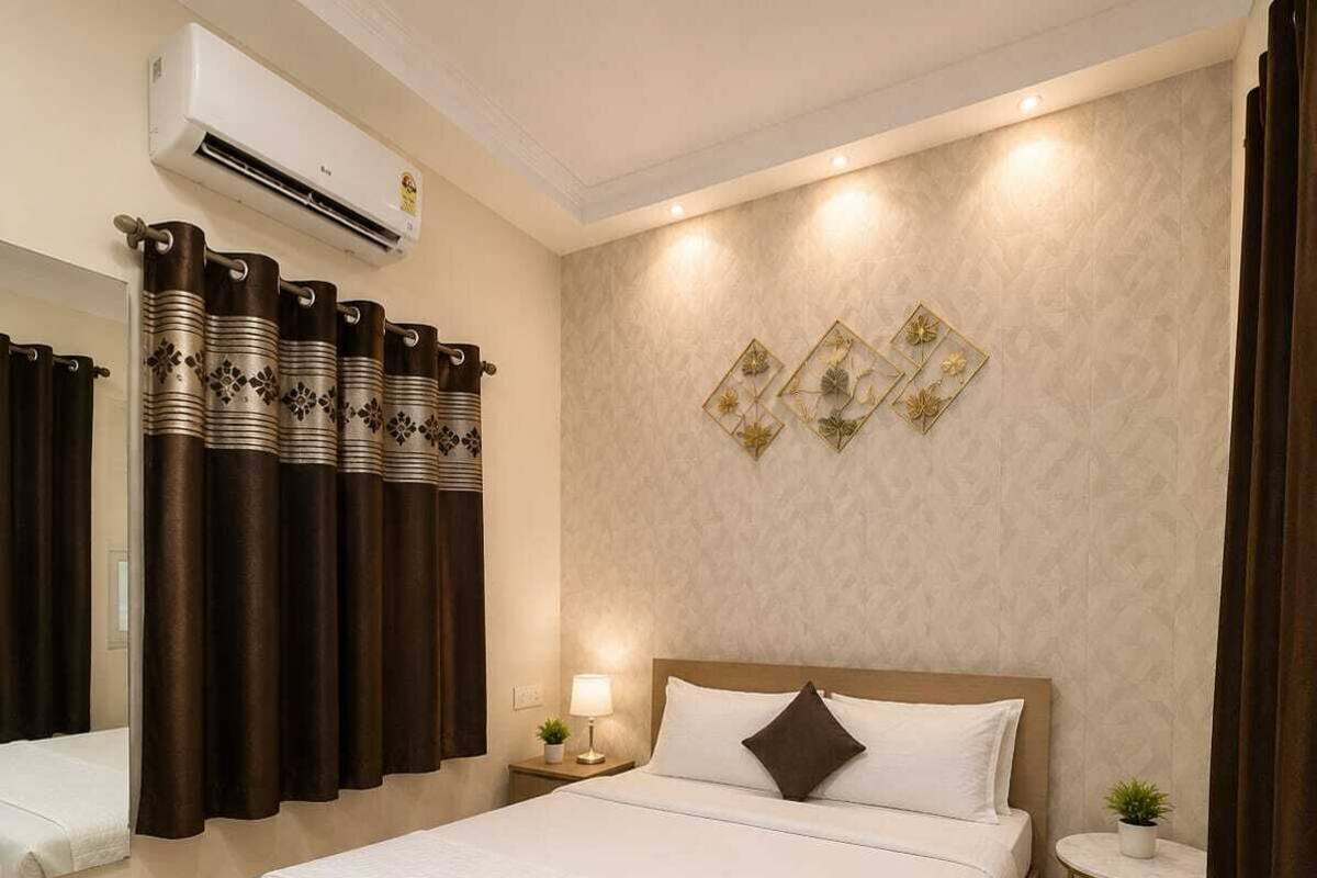 Ein Hotelzimmer mit einem großen Bett, einem Nachttisch mit Lampe, einem kleinen runden Tisch mit Pflanze und einer Wanddekoration.