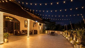 An outdoor patio area with string lights, seating, and potted plants.