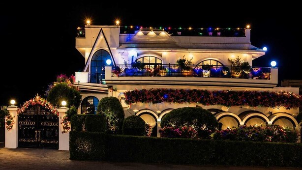 A multi-story building with a grand entrance, arched windows, and a balcony with potted plants.