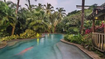 Una piscina rodeada de exuberante vegetación tropical y una estructura de madera.