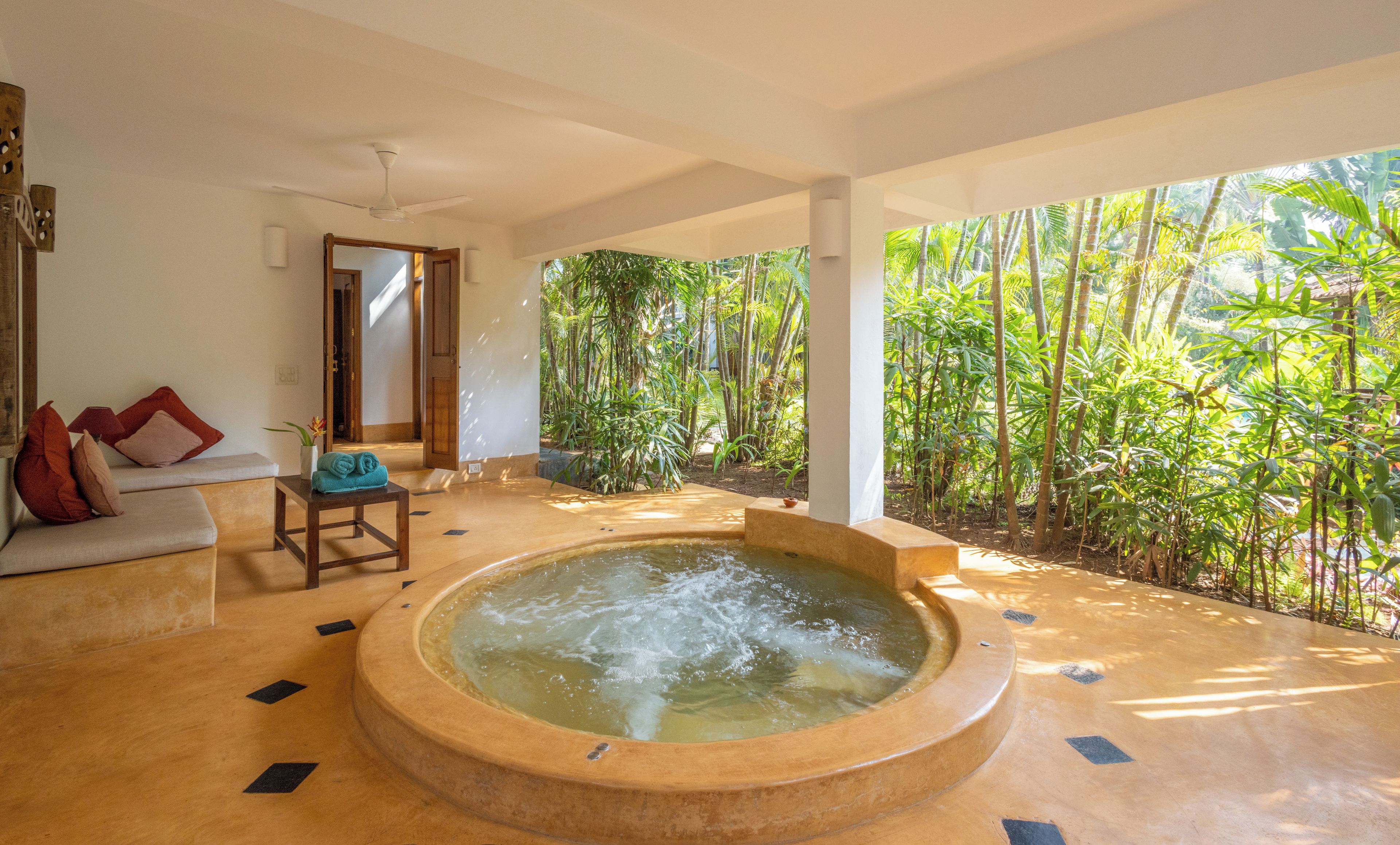 A spa area with a hot tub, seating, and a view of a lush garden.