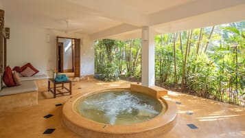 A spa area with a hot tub, seating, and a view of a lush garden.