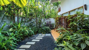 A garden pathway with stepping stones leading to a wooden staircase. - Staymaster Ashvini 2BR Villa Jet Pool (Nerul)