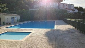 A swimming pool with a tiled deck, a small building with a door, and a fence. - STUNNING APARTMENT (Sainte-Maxime)