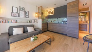 A modern living room with a grey sofa, a wooden coffee table, and a kitchen area with grey cabinets and wooden accents. - STUNNING APARTMENT (Sainte-Maxime)