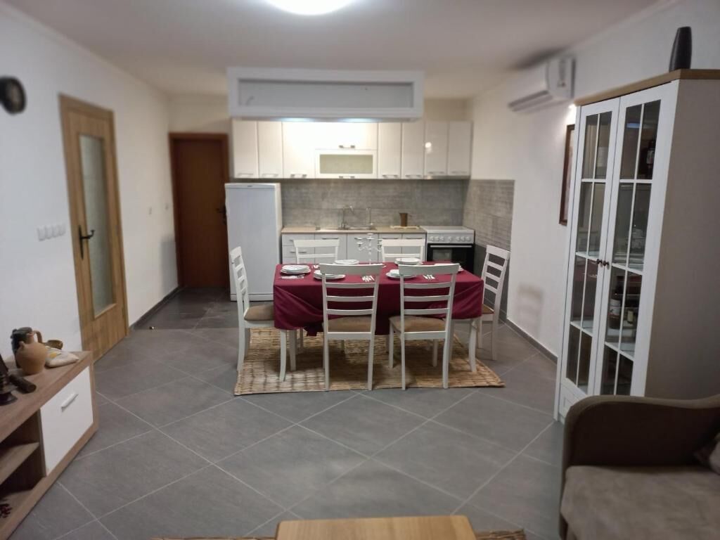 A compact kitchen with white cabinets, a dining table with four chairs, and a refrigerator.