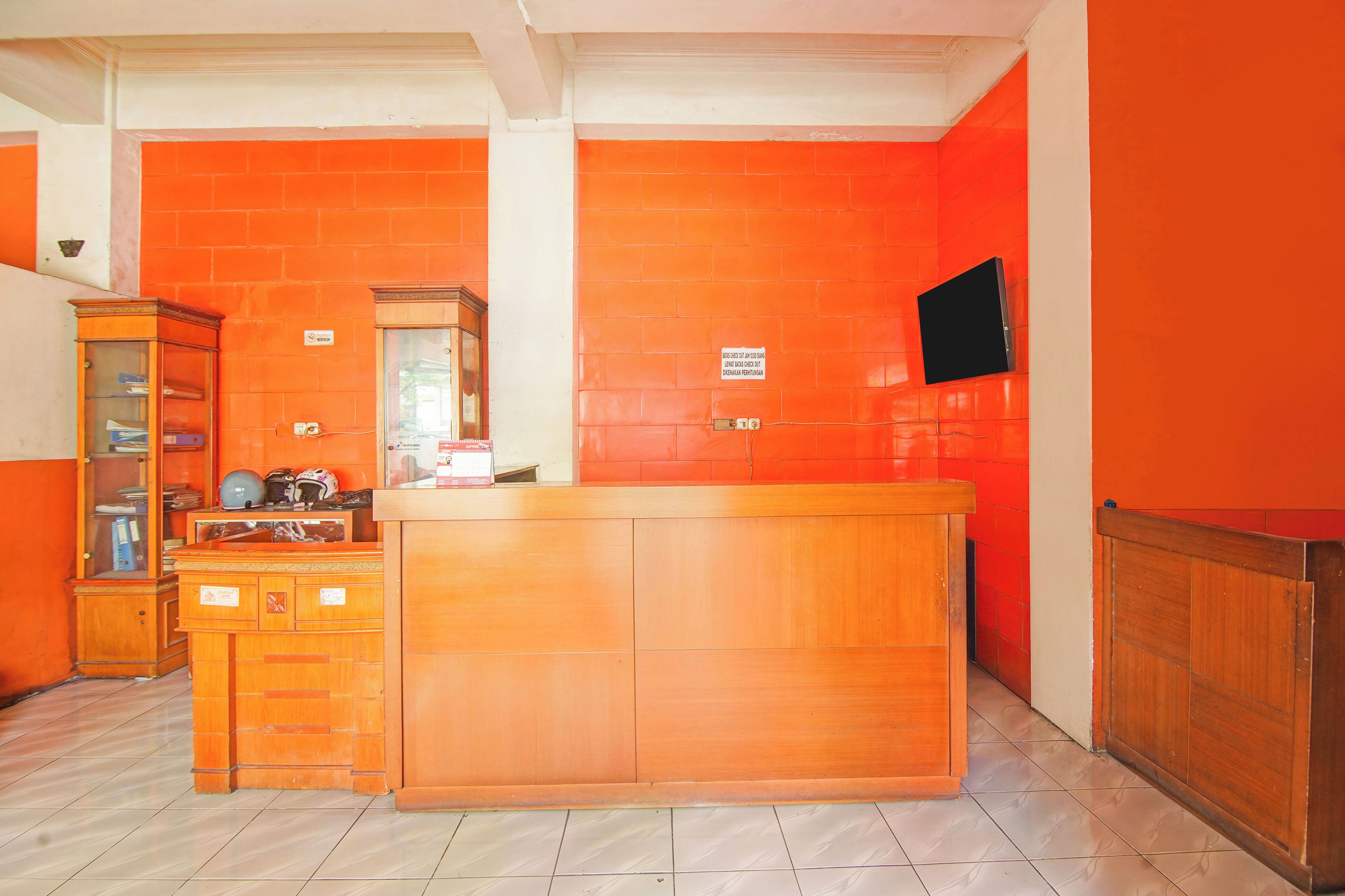 Una habitación con un mostrador de recepción de madera, un aparador de vidrio y suelo de baldosas.