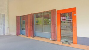Een gebouw met grote ramen, een deur met een oranje frame en een zichtbaar bord.