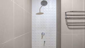 Een douche met een handdouche en een kraan op de muur.
