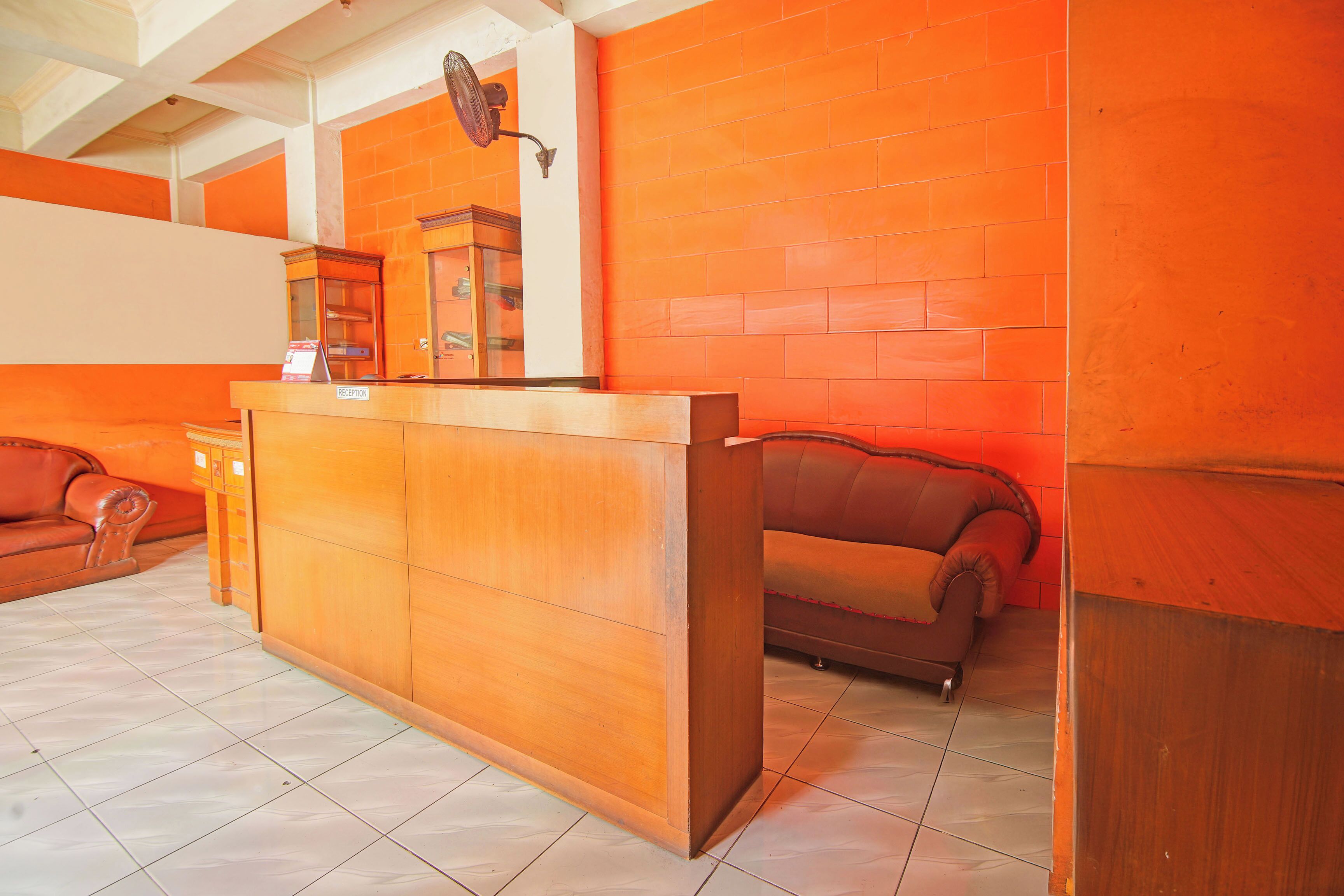 A reception area with a wooden counter, a glass display case, and two leather sofas.