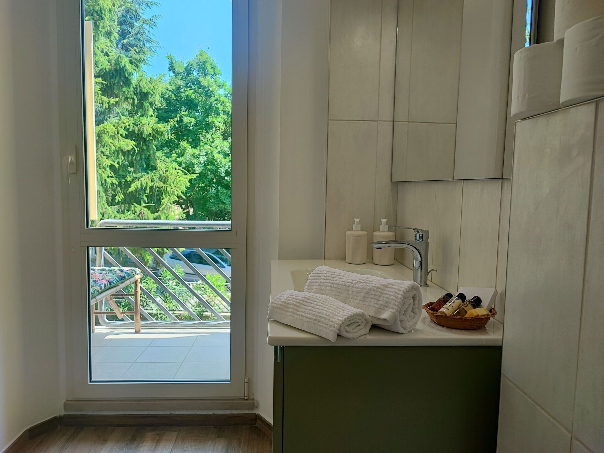 A bathroom with a large window, a sink with toiletries, and a towel.