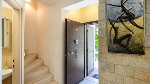 Un interior moderno con una escalera, una puerta oscura y una obra de arte colgada en la pared.