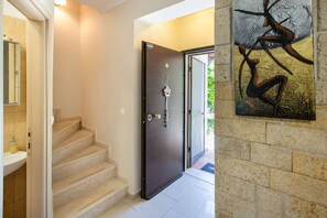 A modern interior with a staircase, a dark door, and a wall-mounted artwork. - Saba Villa by RentalsPro - Hanioti (Paliouri)