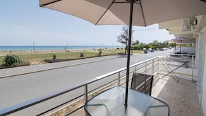 Un balcone con vista sulla spiaggia, un tavolo e delle sedie.