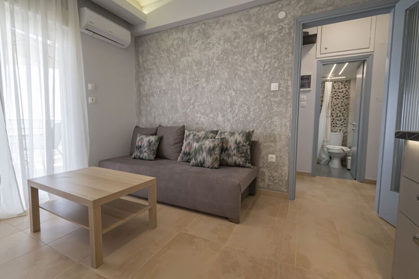 A modern living room with a sofa, a wooden table, and a grey textured wall.