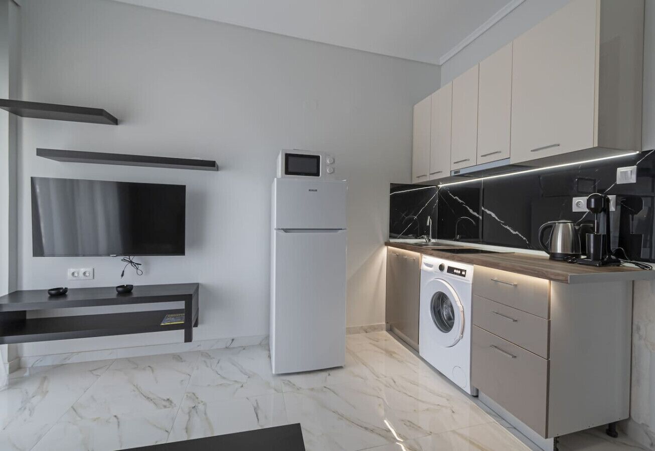 A modern kitchen with a built-in washer, a flat-screen TV, and a minimalist design.