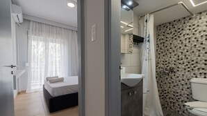 Une chambre d’hôtel moderne équipée d’un lit, d’une salle de bain avec douche et d’un lavabo.