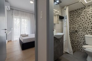 A modern hotel room with a bed, a bathroom with a shower, and a sink. - Happy Ellen Seafront 6 by Travel Pro Services (Nea Plagia)