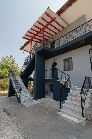 Ein zweistöckiges Gebäude mit Treppe, einem Balkon mit roter Geländer und einem Fenster.