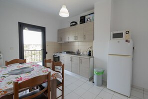 A compact kitchen with a dining table, chairs, a microwave, and a refrigerator.