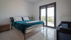 Et soveværelse med en seng, et natbord, en stol, en potteplante og en skydedør til en balkon.