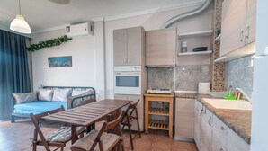 Ett kompakt bostadsutrymme med ett litet kök, en matplats och en soffa.