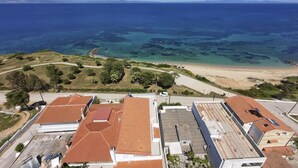 Vue aérienne d’une zone côtière avec des bâtiments, une plage et une mer bleue et limpide.