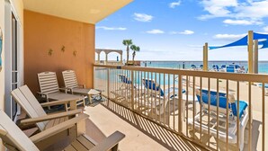 A balcony with lounge chairs, a pool, and a view of the beach. - NEW Sunrise Beach 510! FREE Beach Service, Heated Pool, FREE Golf & Perks! (Panama City Beach)