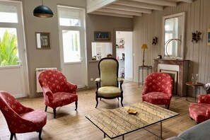 A living room with wooden flooring, a patterned coffee table, and floral upholstered chairs.