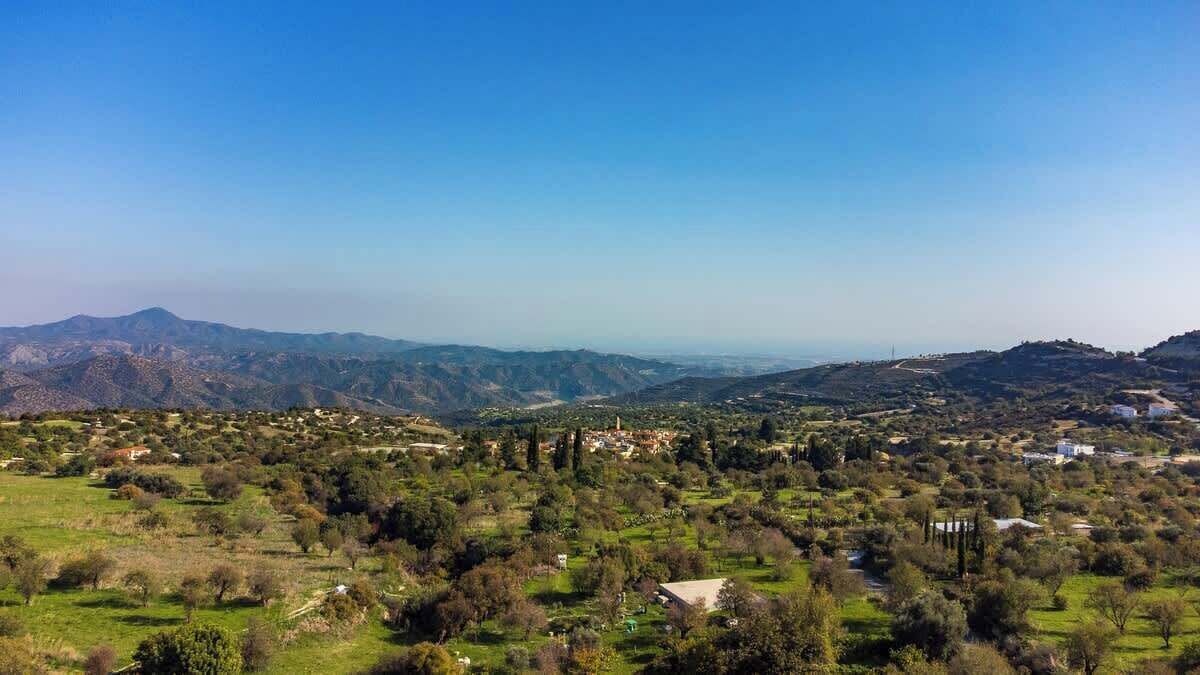 Panoramica di un paesaggio montuoso con edifici sparsi e vegetazione.