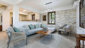 Moderni olohuone, jossa on kivestä tehty korosteseinä, sohva, sohvapöytä ja ruokailutila.